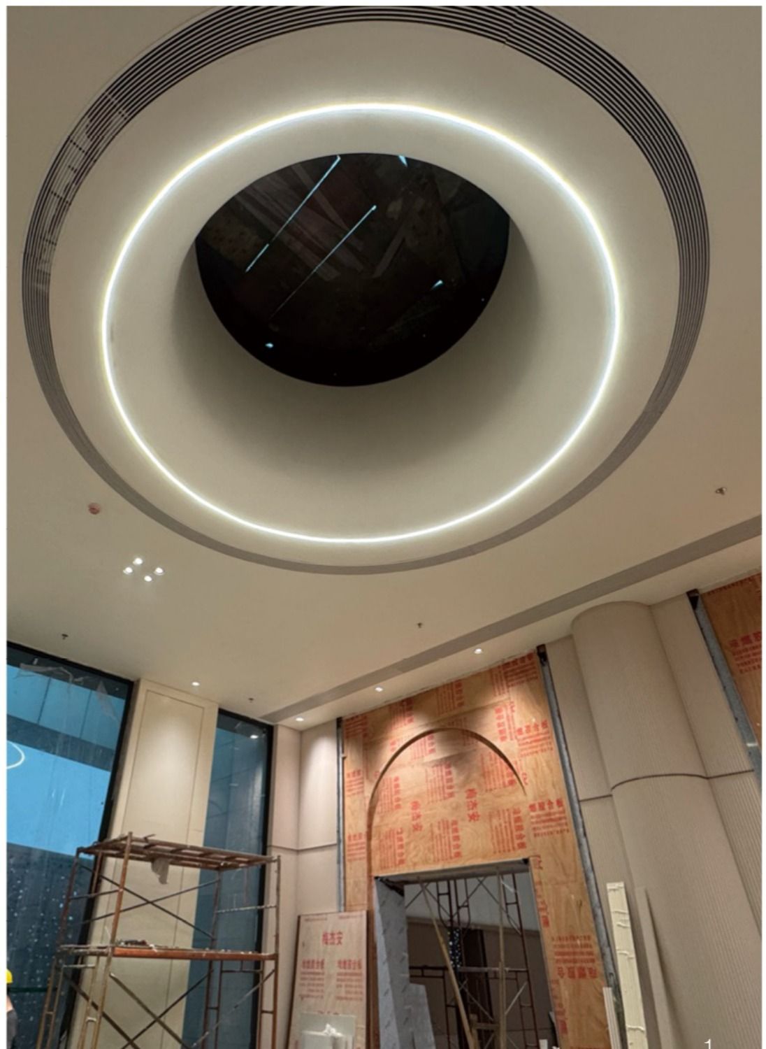 Photo of a curved skylight atrium under construction, showing the illuminated ring ceiling and scaffolding below